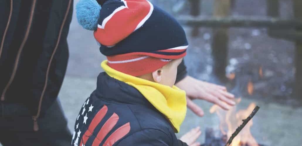 little boy warming up by fire