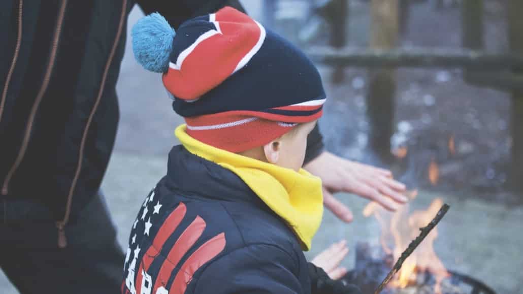 little boy warming up by fire