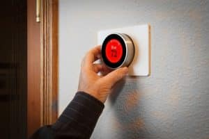 hand adjusting a digital thermostat