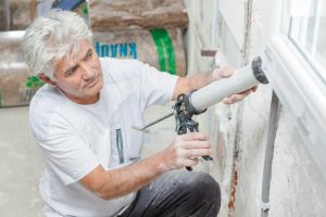 man sealing window
