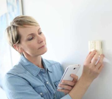 woman adjusting thermostat on wall