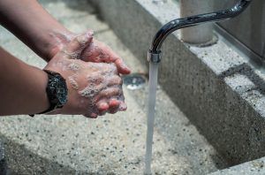 man washing hands at running faucet