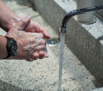 Man washing hands at running faucet