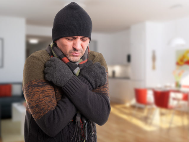 man shivering inside of cold house
