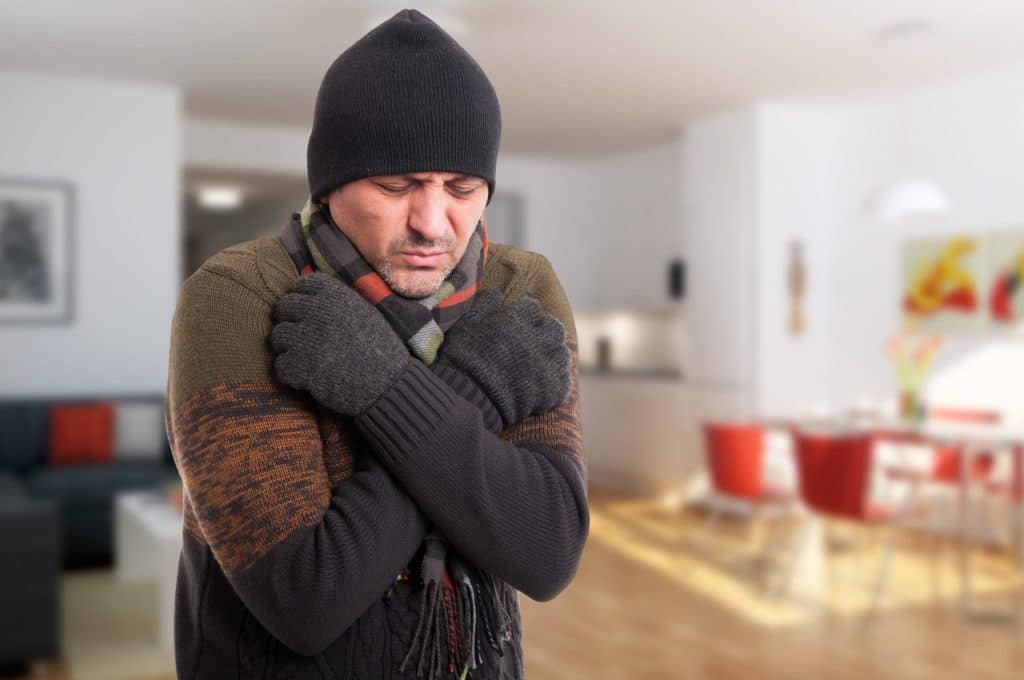 man shivering inside of cold house
